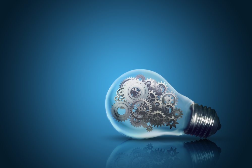 Close up of light bulb with gear mechanism inside isolated on dark blue background.jpeg